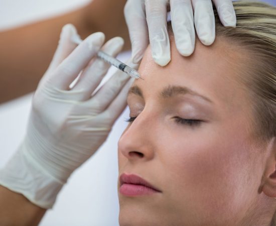 Close-up of female patient receiving a botox injection on forehead